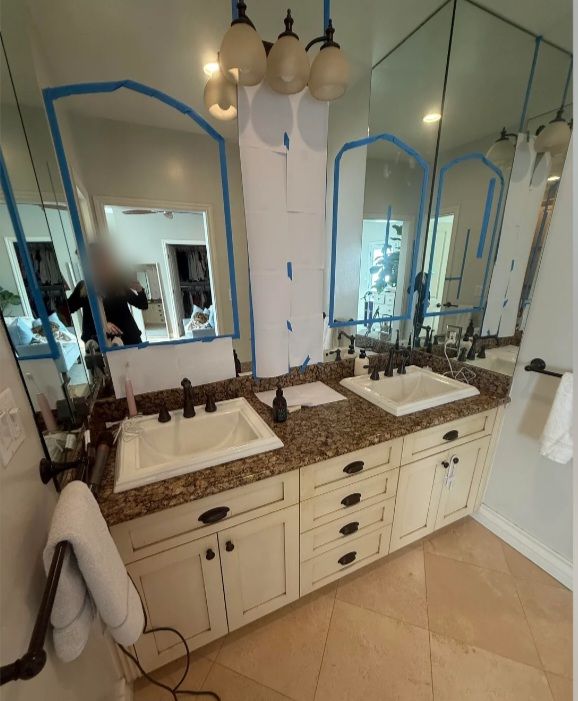 Bathroom before: cream double vanity with a dark granite top and taped mirrors.