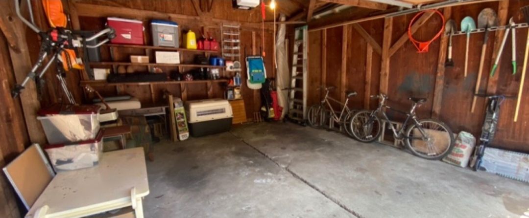 Detached garage after: clear floor, shelves organized, bikes parked and tools hung on the wall.