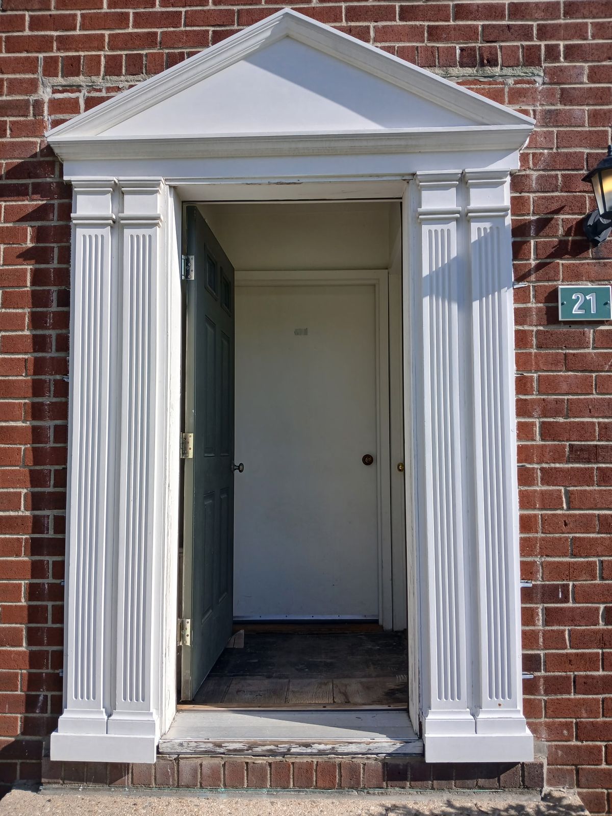 Entry 21 before: open door to a vestibule with a bare, worn floor and a weathered threshold.